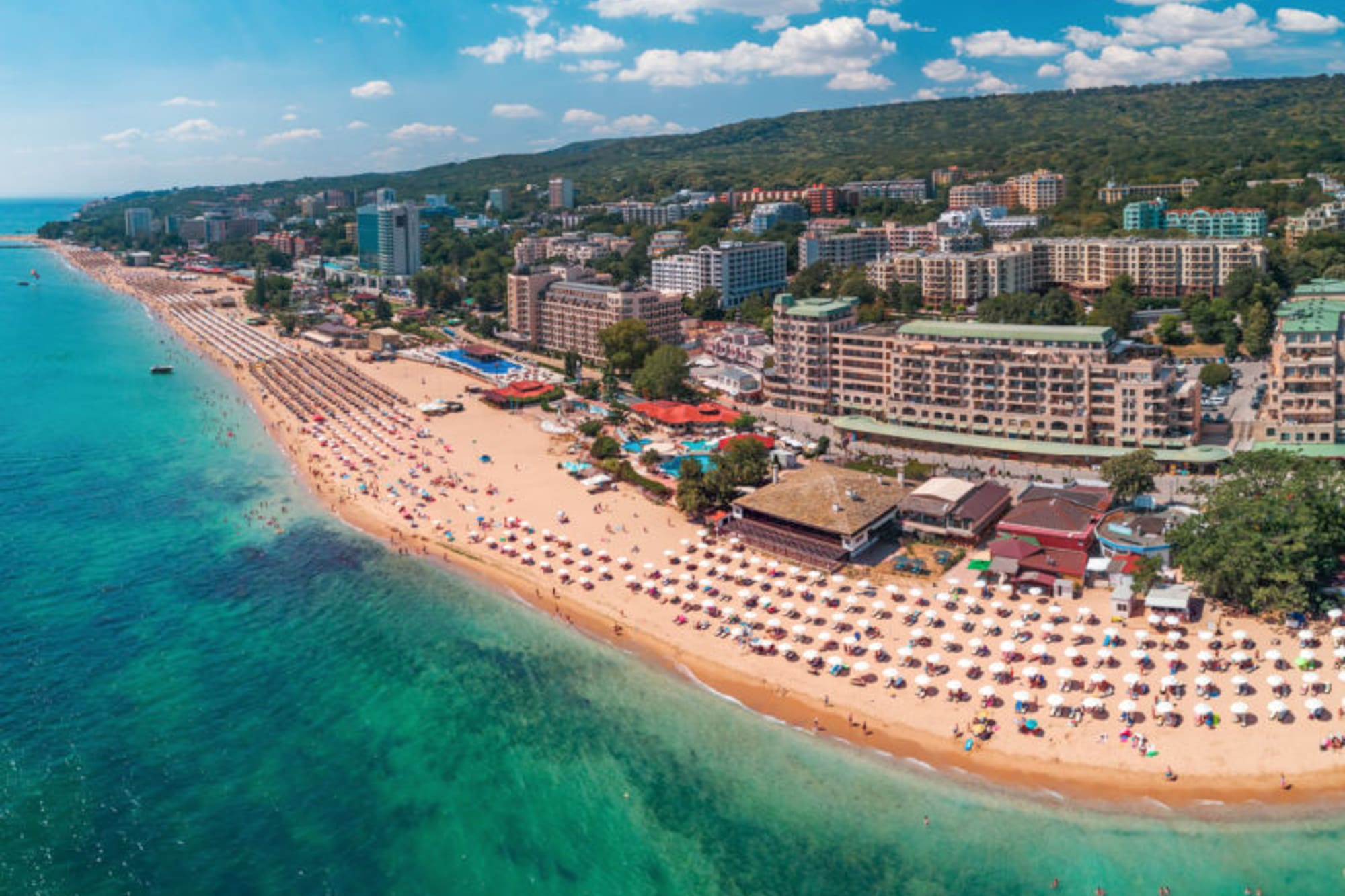a beach with buildings and umbrellas and buildings on the shore