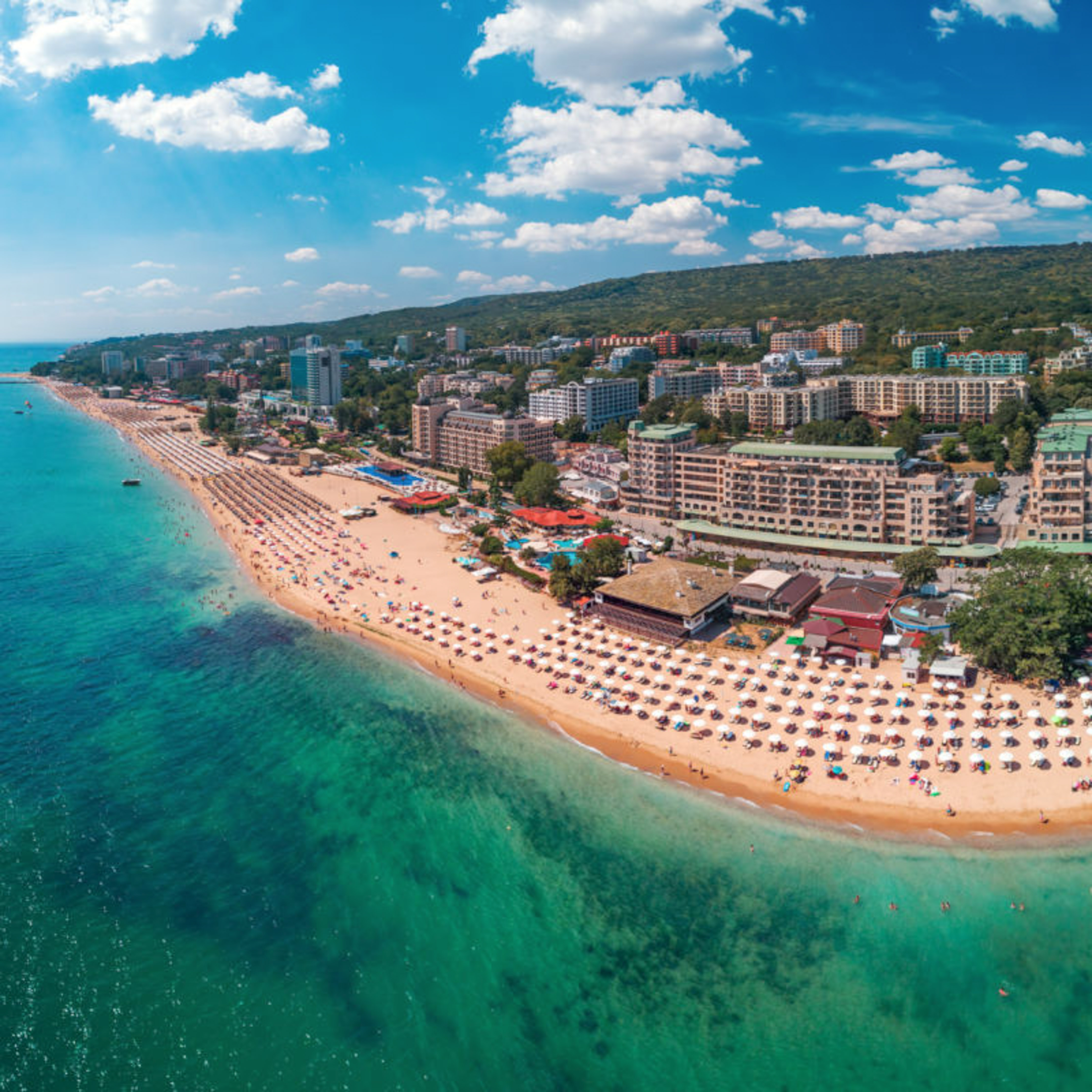 a beach with buildings and umbrellas and buildings on the shore