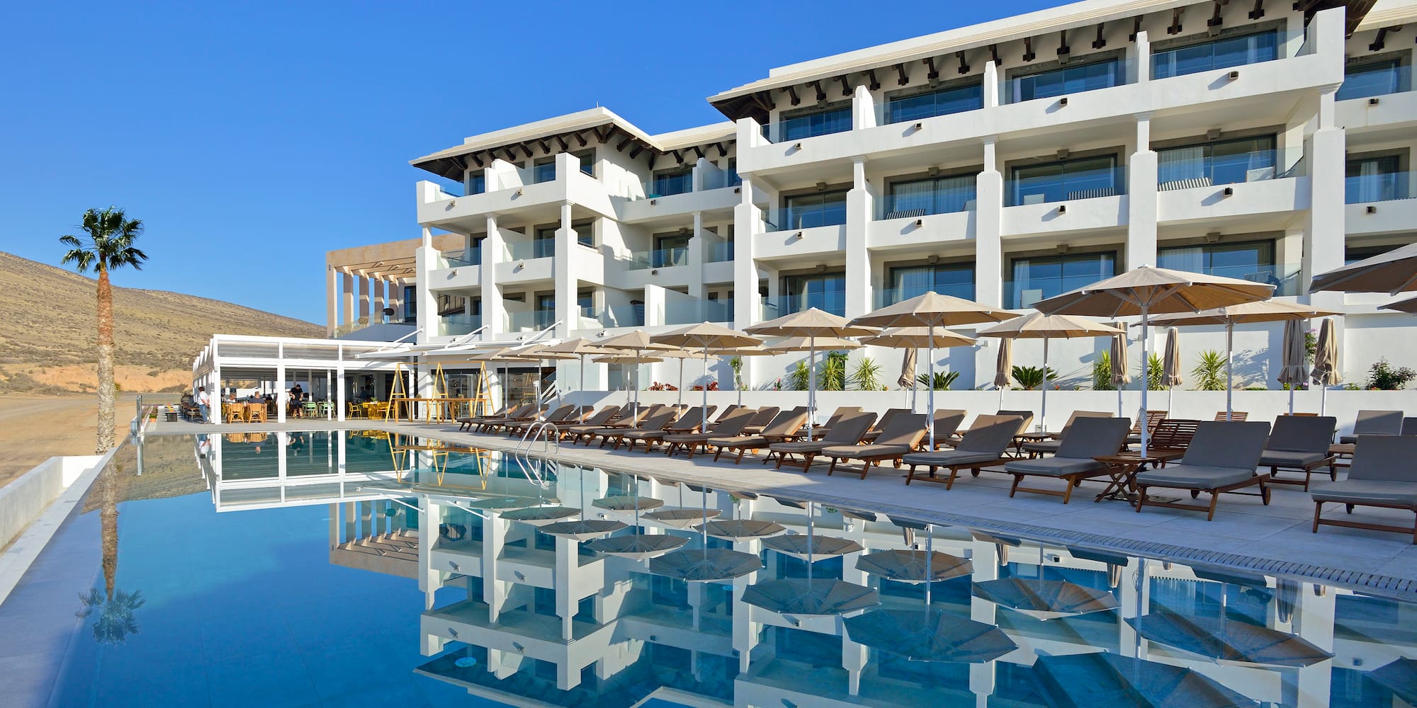 a pool with lounge chairs and umbrellas in front of a building