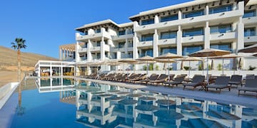 a pool with lounge chairs and umbrellas in front of a building