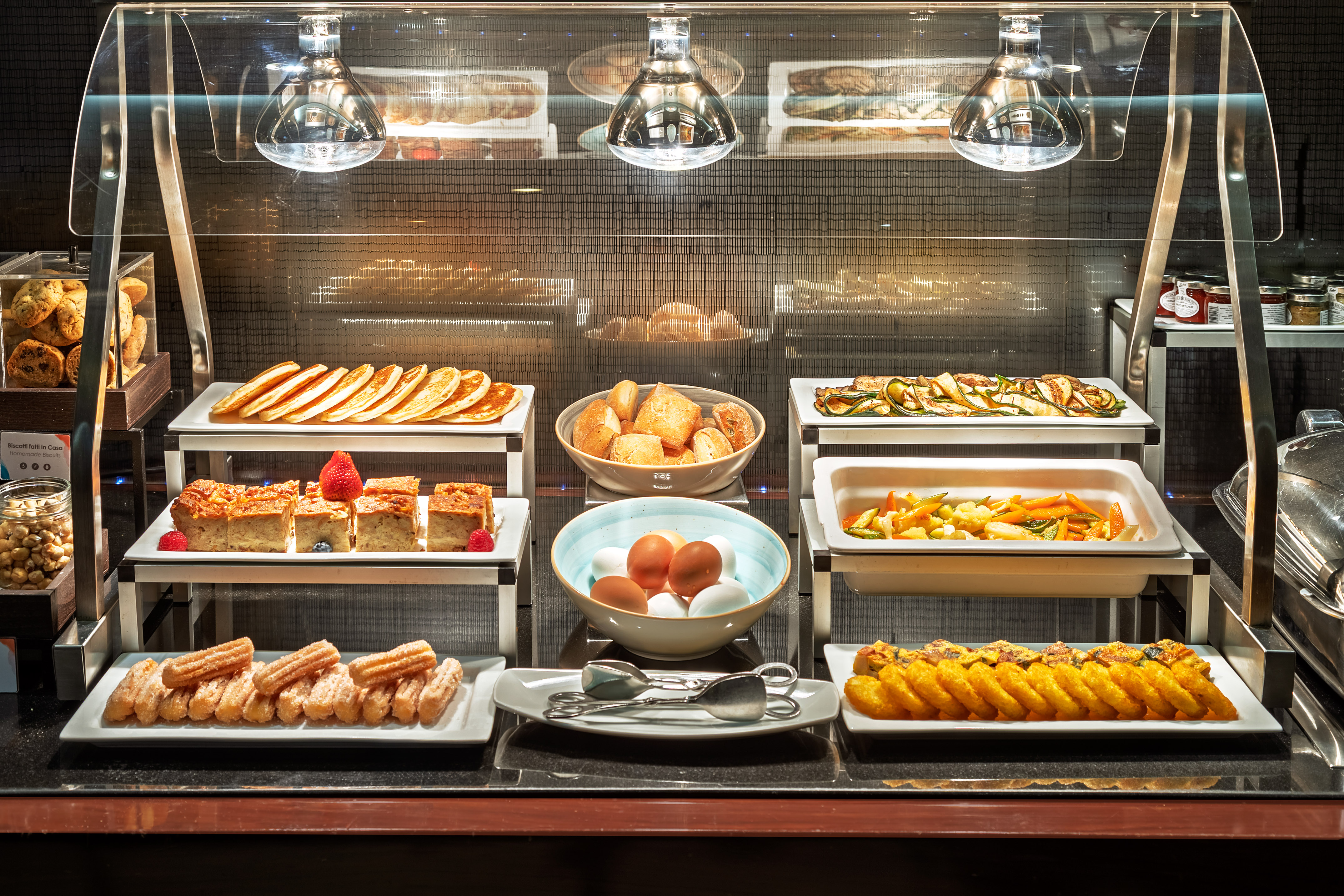 Full breakfast buffet with pancakes, pastries, eggs, churros, and roasted vegetables.
