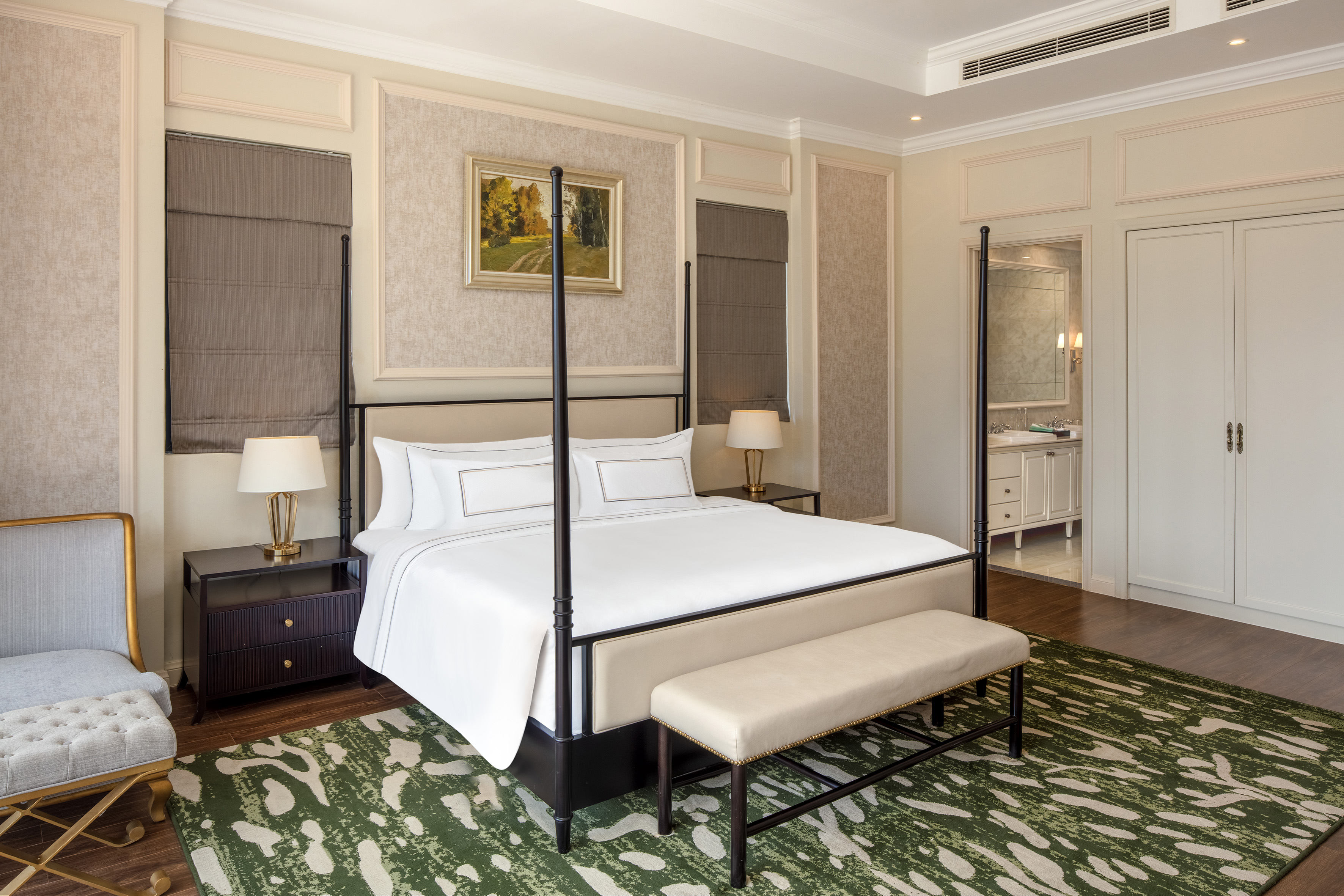 Elegant luxury bedroom with four-poster bed, green rug, and en-suite bathroom view.