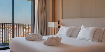 a bed with white sheets and towels on it