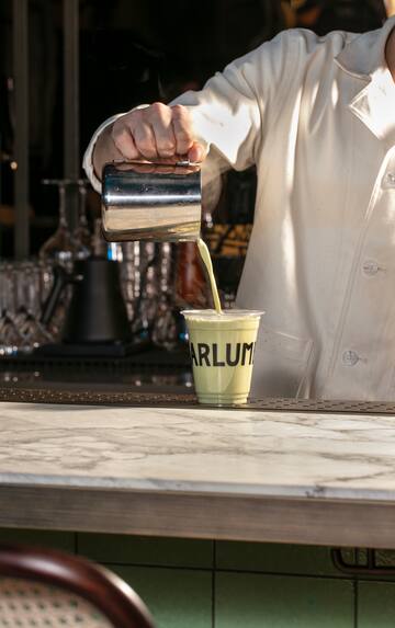 a person pouring a drink into a cup