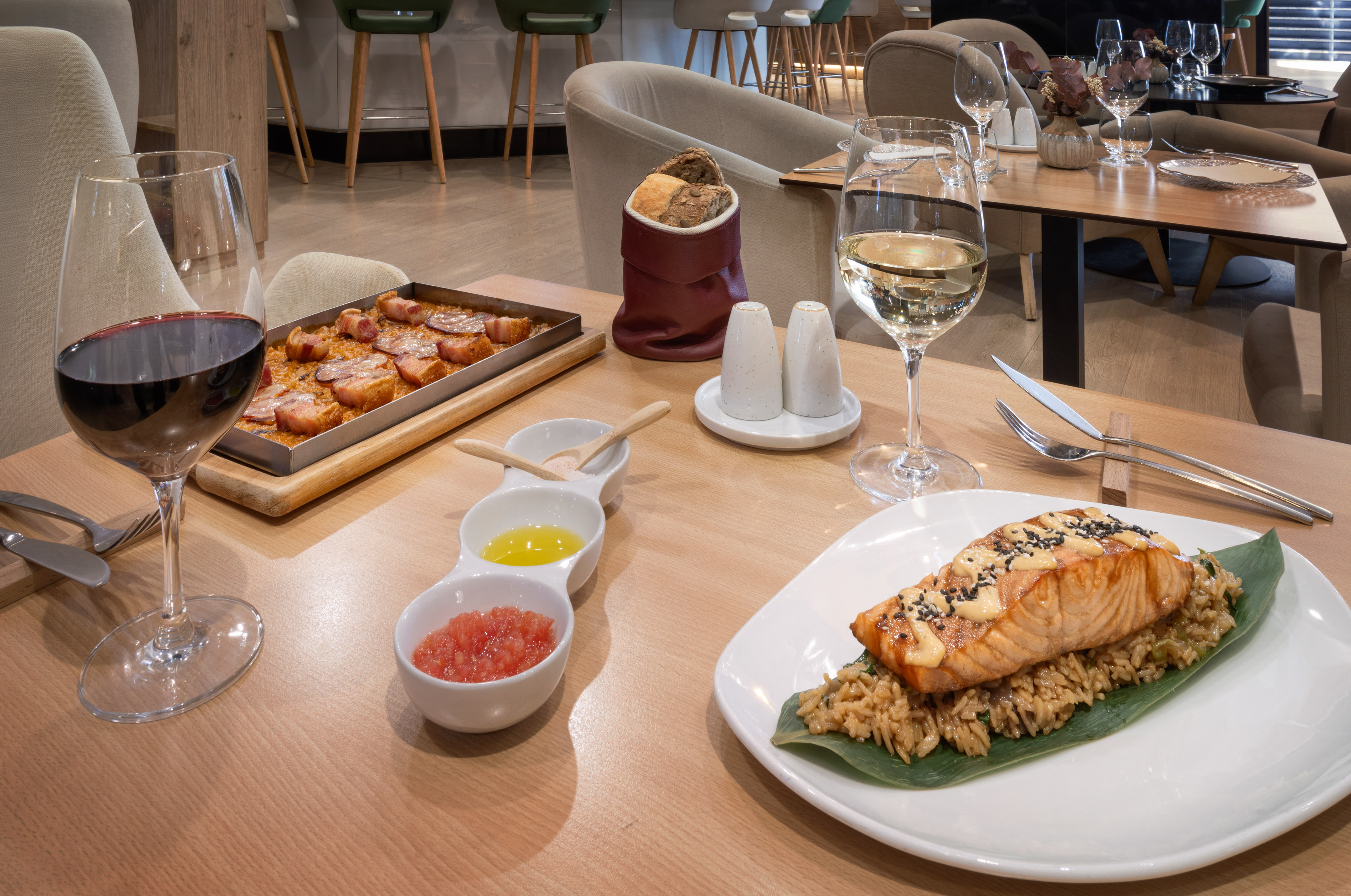 Restaurant dining with salmon, rice, a savory bacon dish, red and white wine.