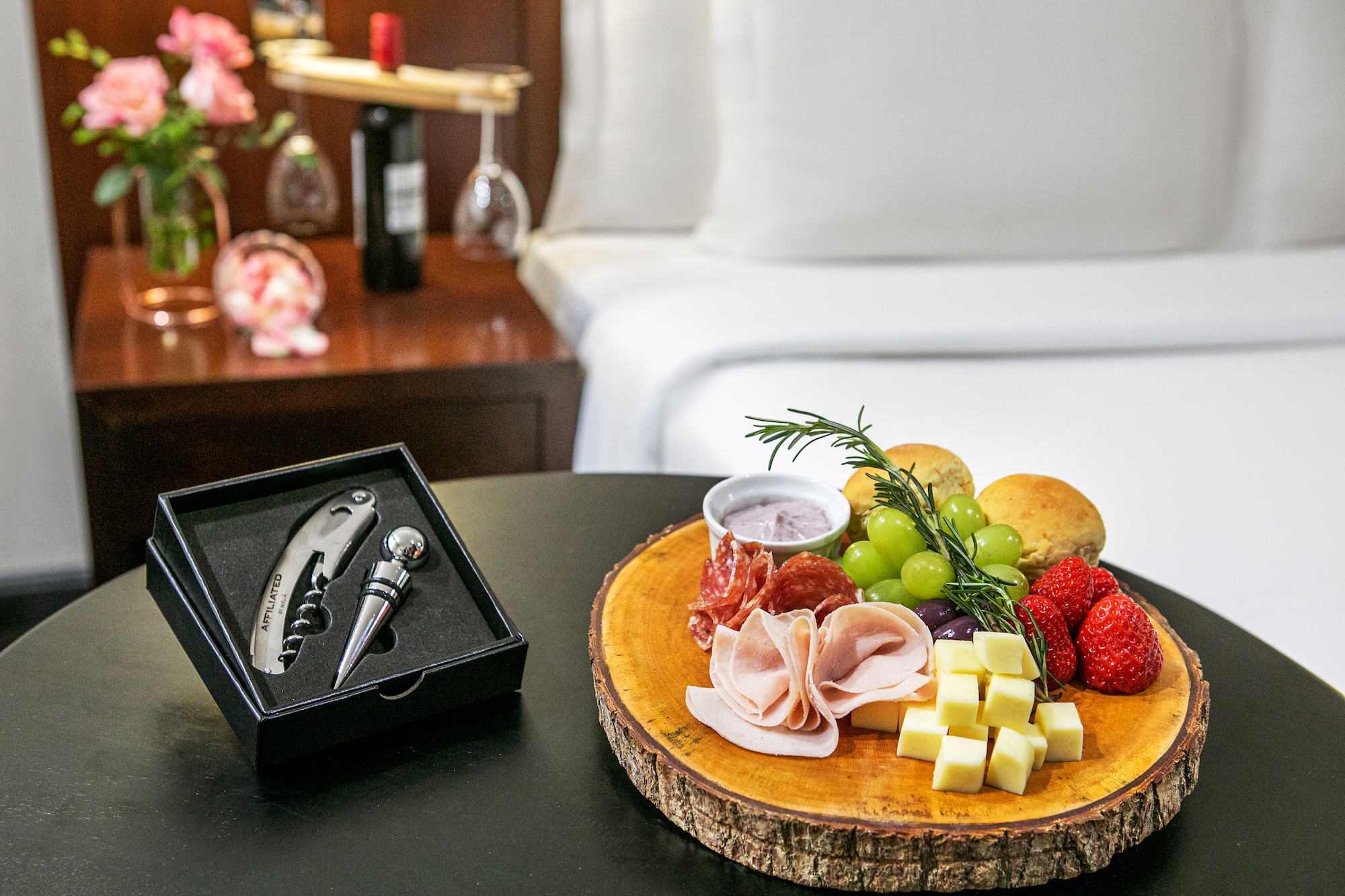 Hotel charcuterie board with cheese, meats, fruit, and wine opener set.