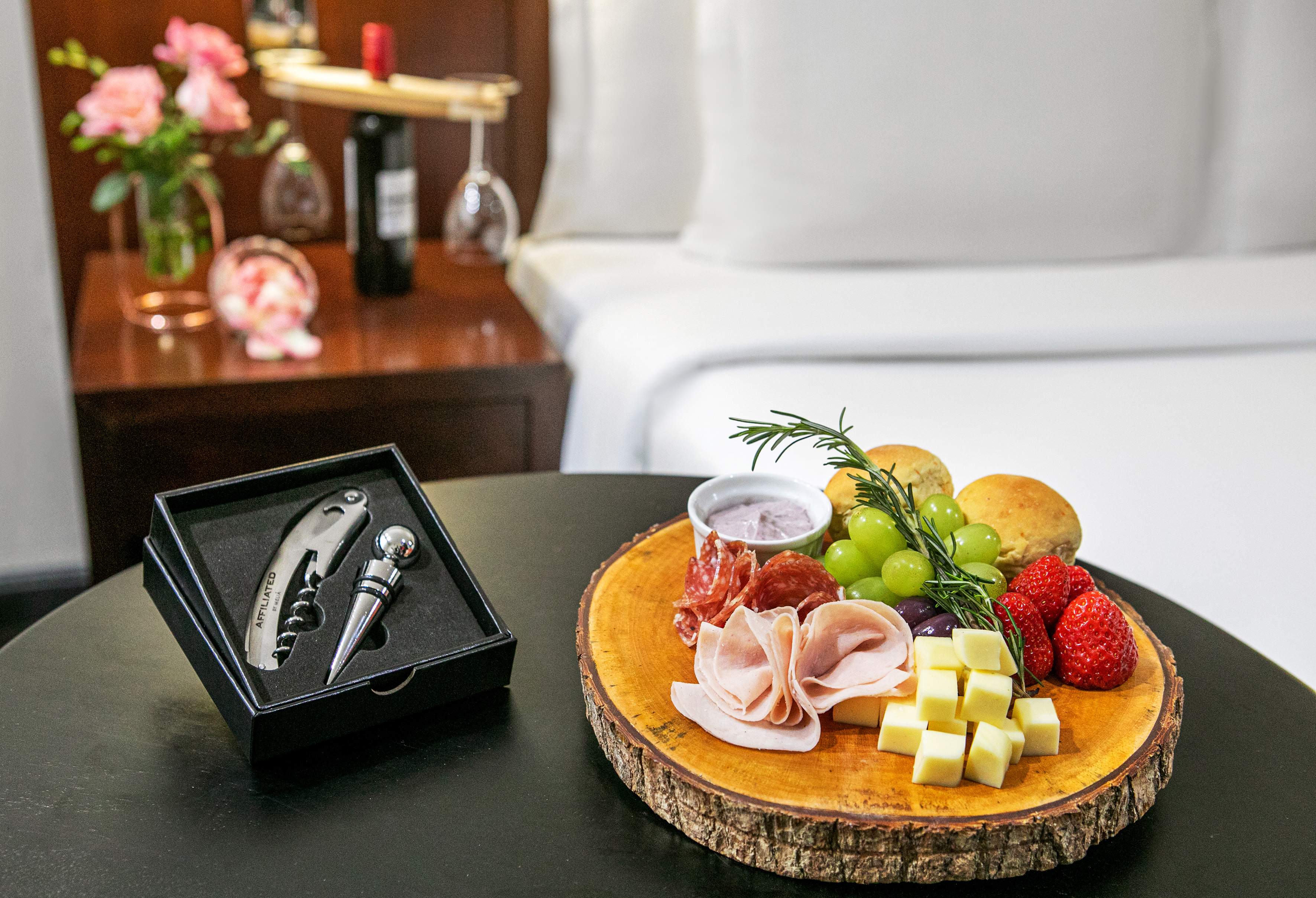 Hotel charcuterie board with cheese, meats, fruit, and wine opener set.