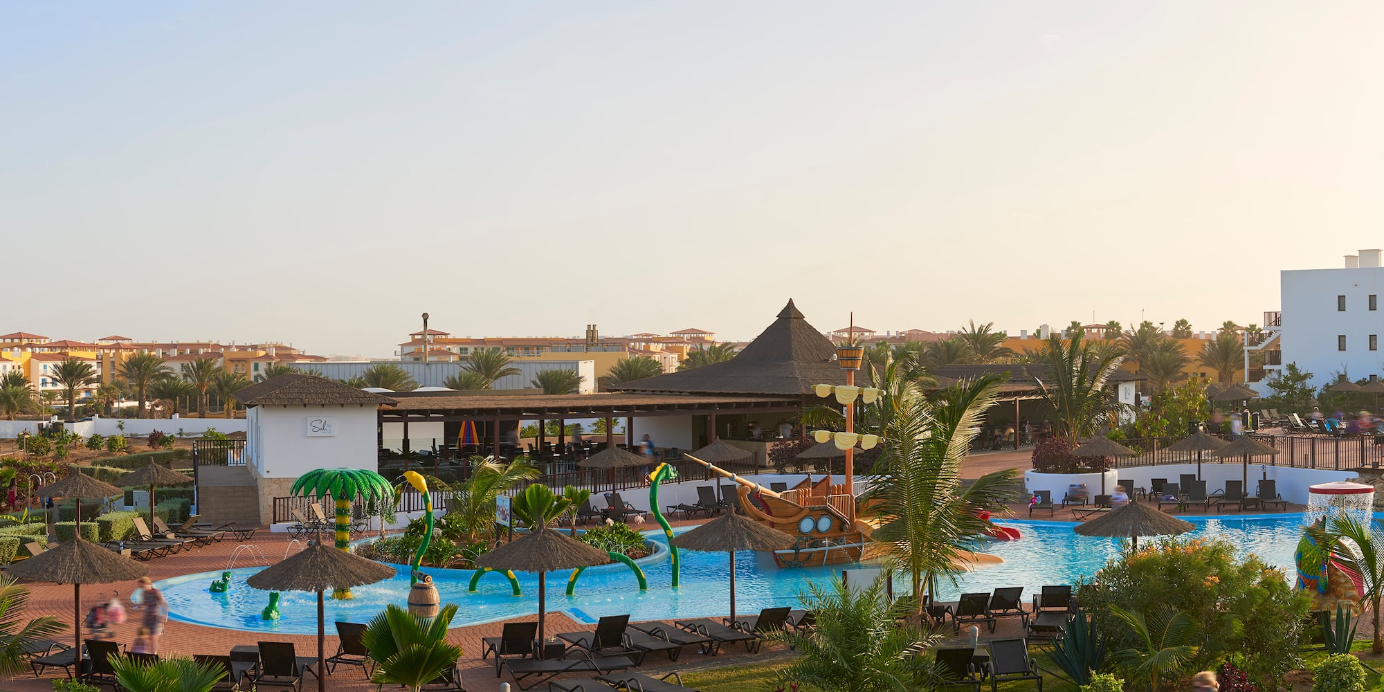 a pool with lounge chairs and umbrellas in a resort