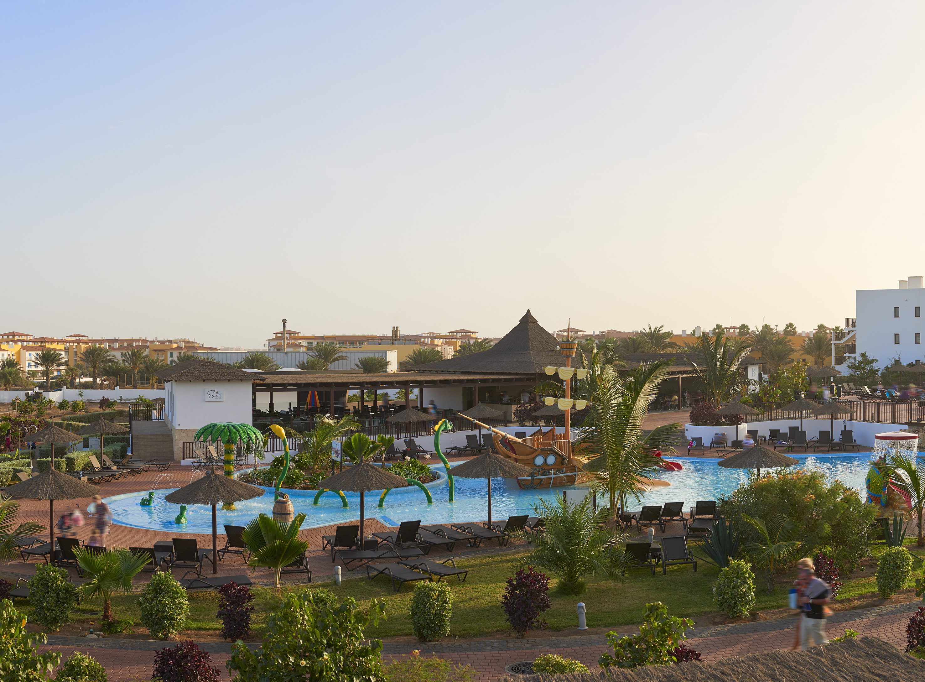 a pool with lounge chairs and umbrellas in a resort