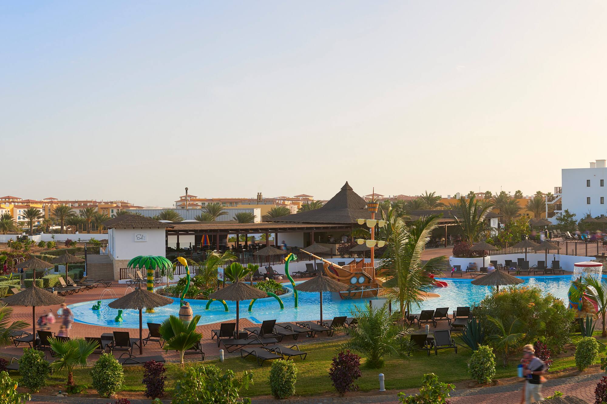a pool with lounge chairs and umbrellas in a resort