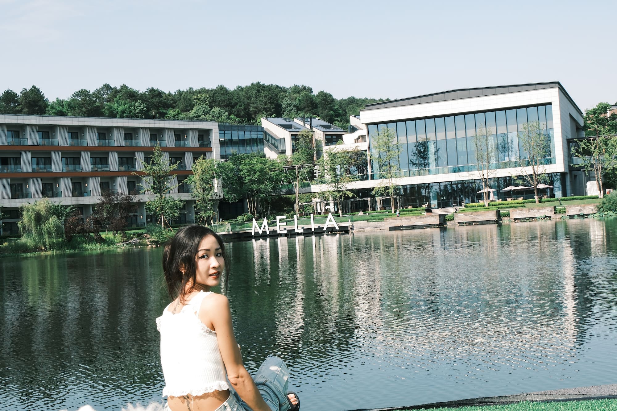a woman sitting on grass next to a body of water