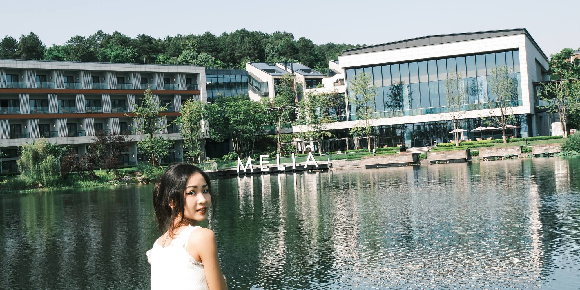 a woman sitting on grass next to a body of water