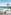 Resort balcony with rocking chair, beach, palm trees, and clear blue sea view.