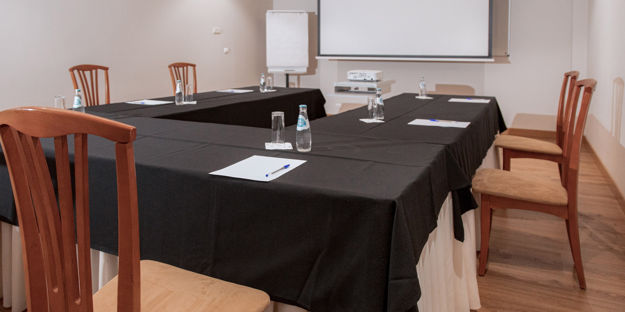 a room with a large table with chairs and a projector screen