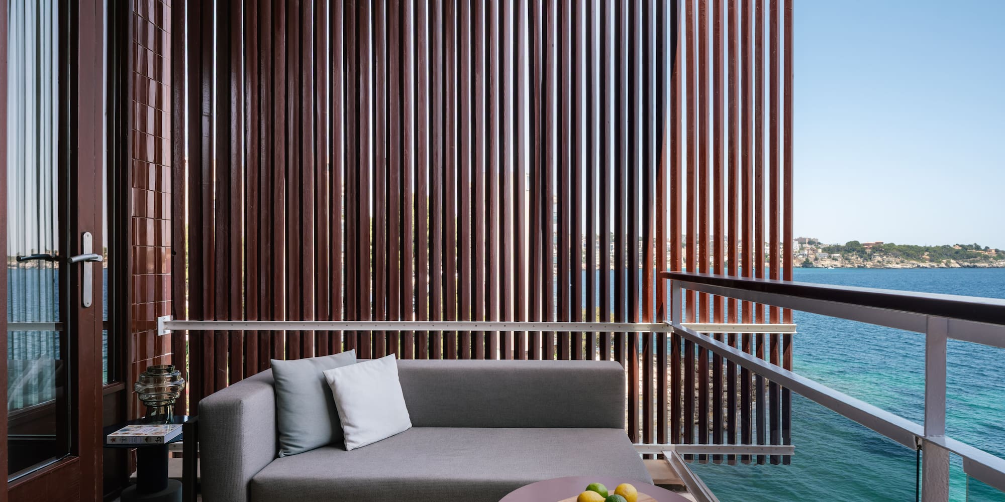 a couch and a table on a balcony overlooking water