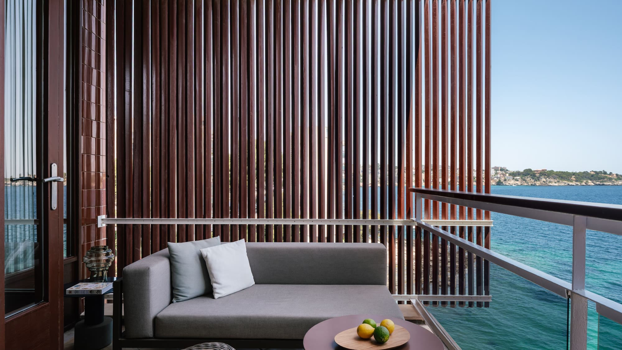 a couch and a table on a balcony overlooking water