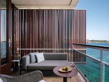 a couch and a table on a balcony overlooking water