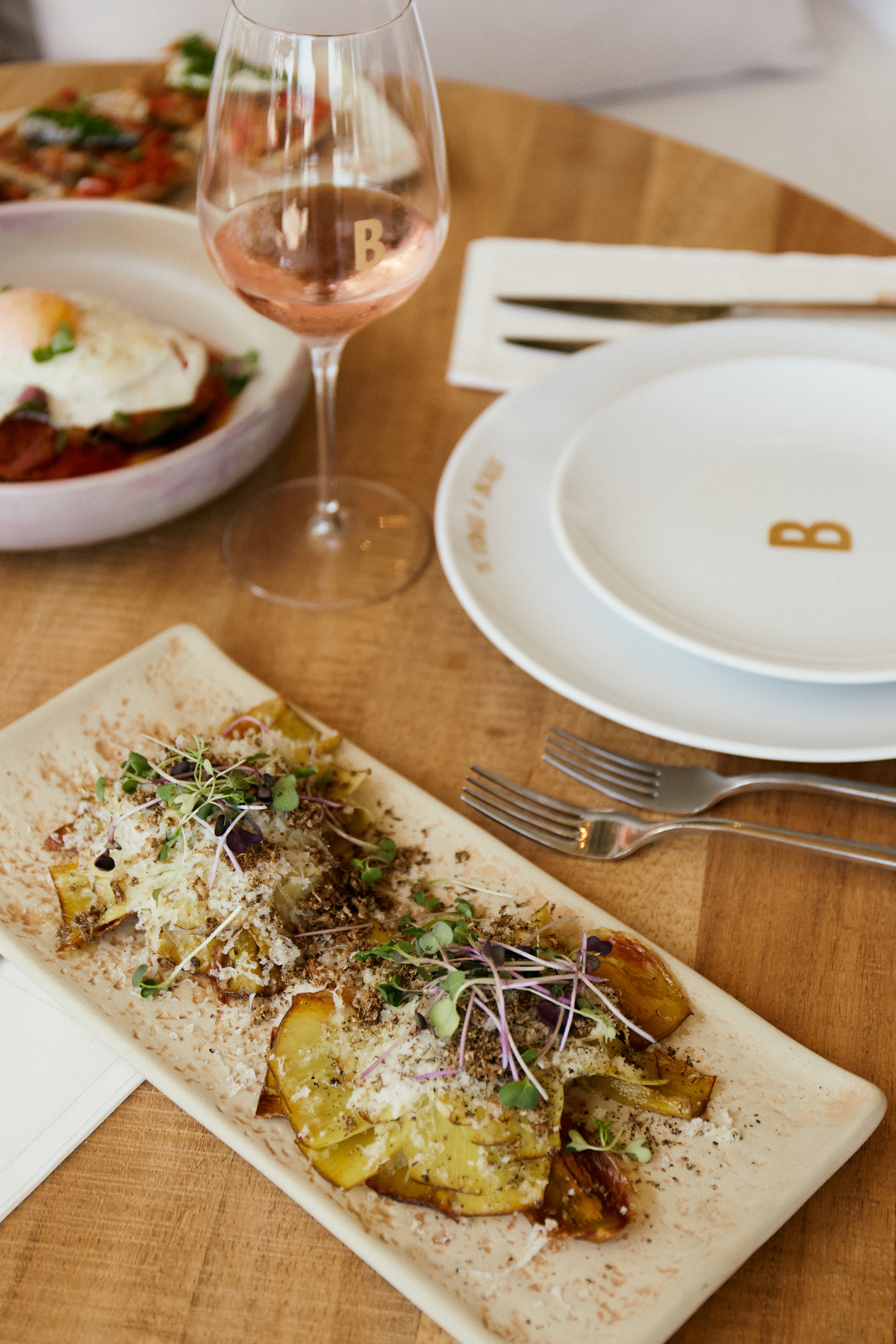 Roasted vegetable dish with microgreens, parmesan, and rosé wine for brunch.