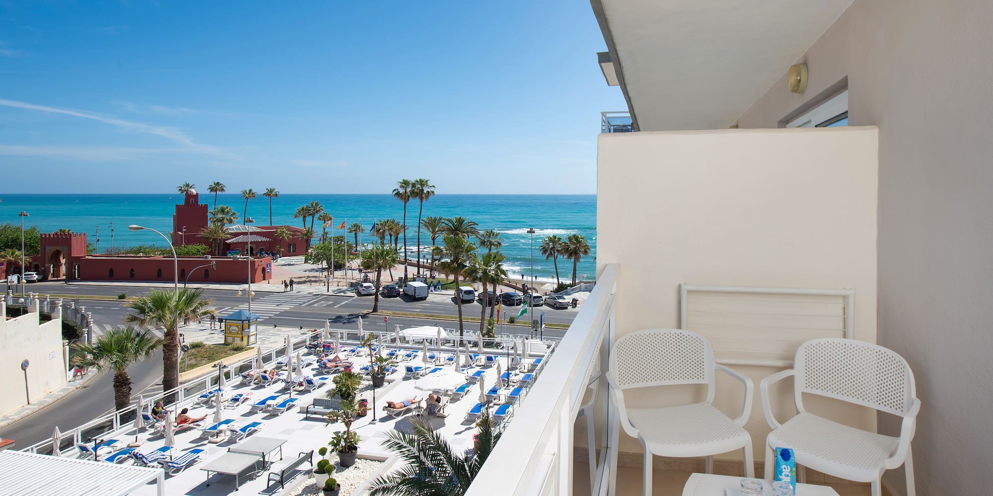 a balcony with chairs and tables and a beach