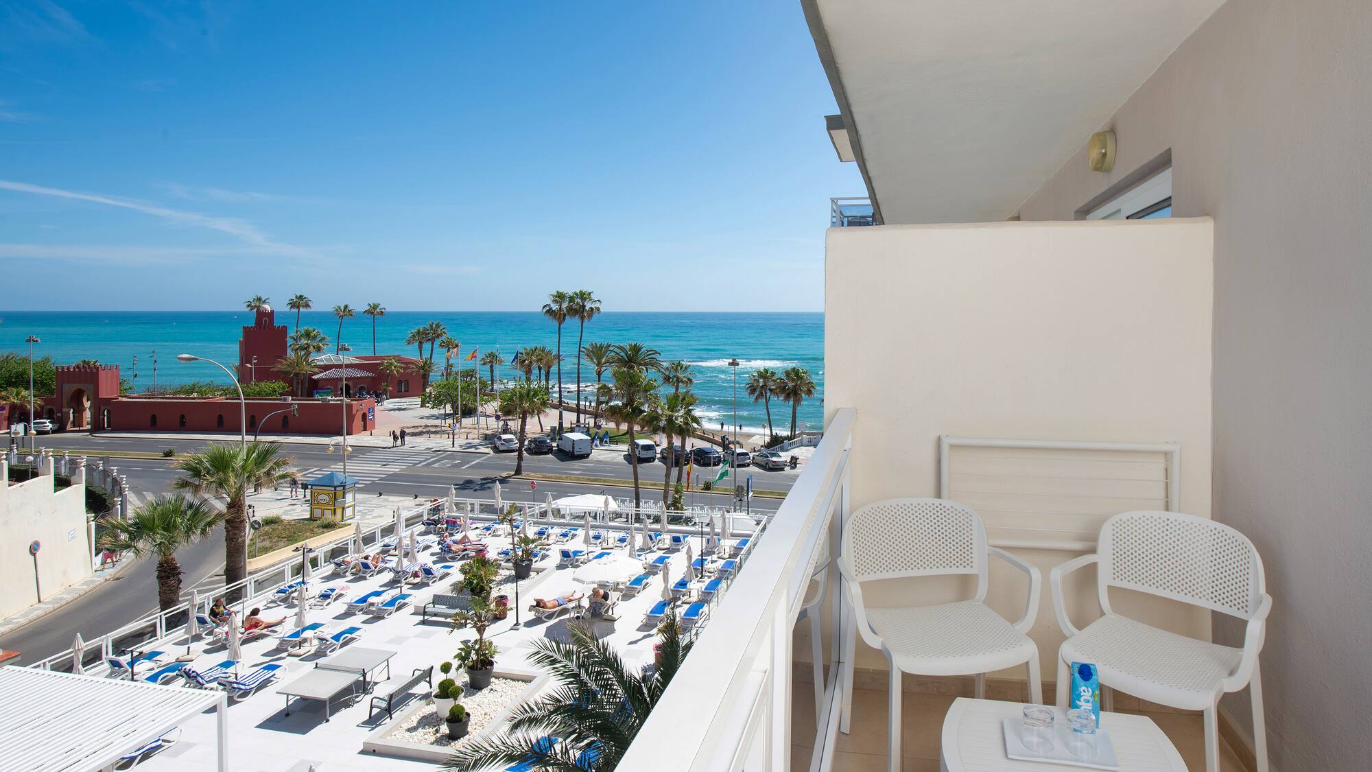 a balcony with chairs and tables and a beach