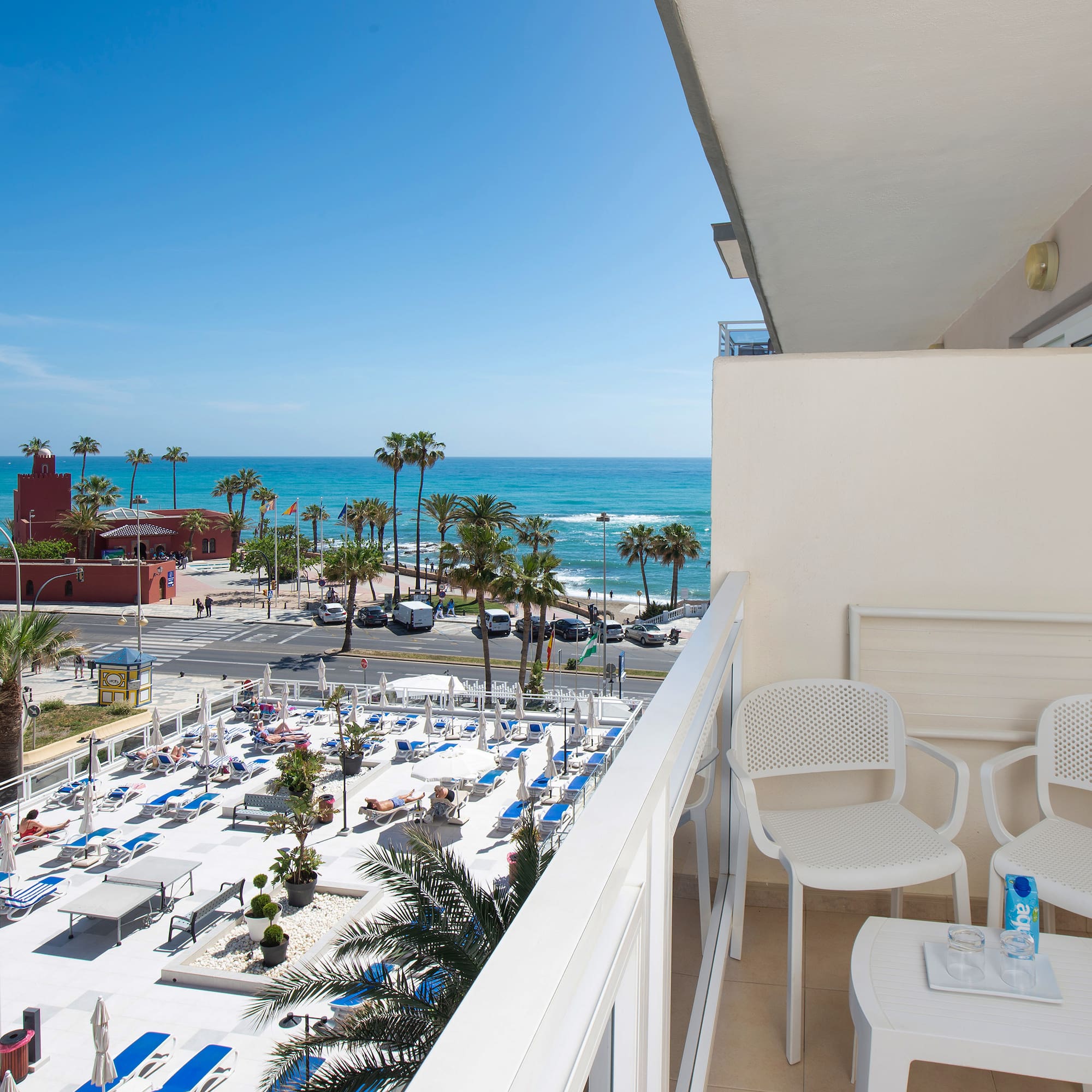 a balcony with chairs and tables and a beach