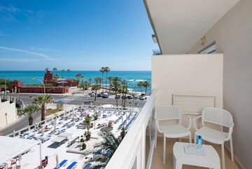 a balcony with chairs and tables and a beach