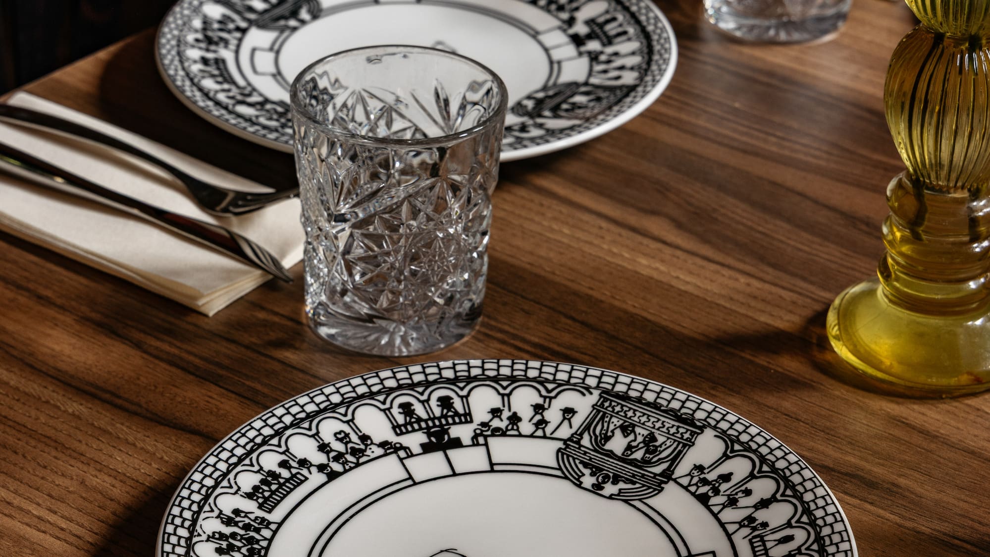 Mesa de restaurante con platos Burladero, vasos de cristal y cubiertos.