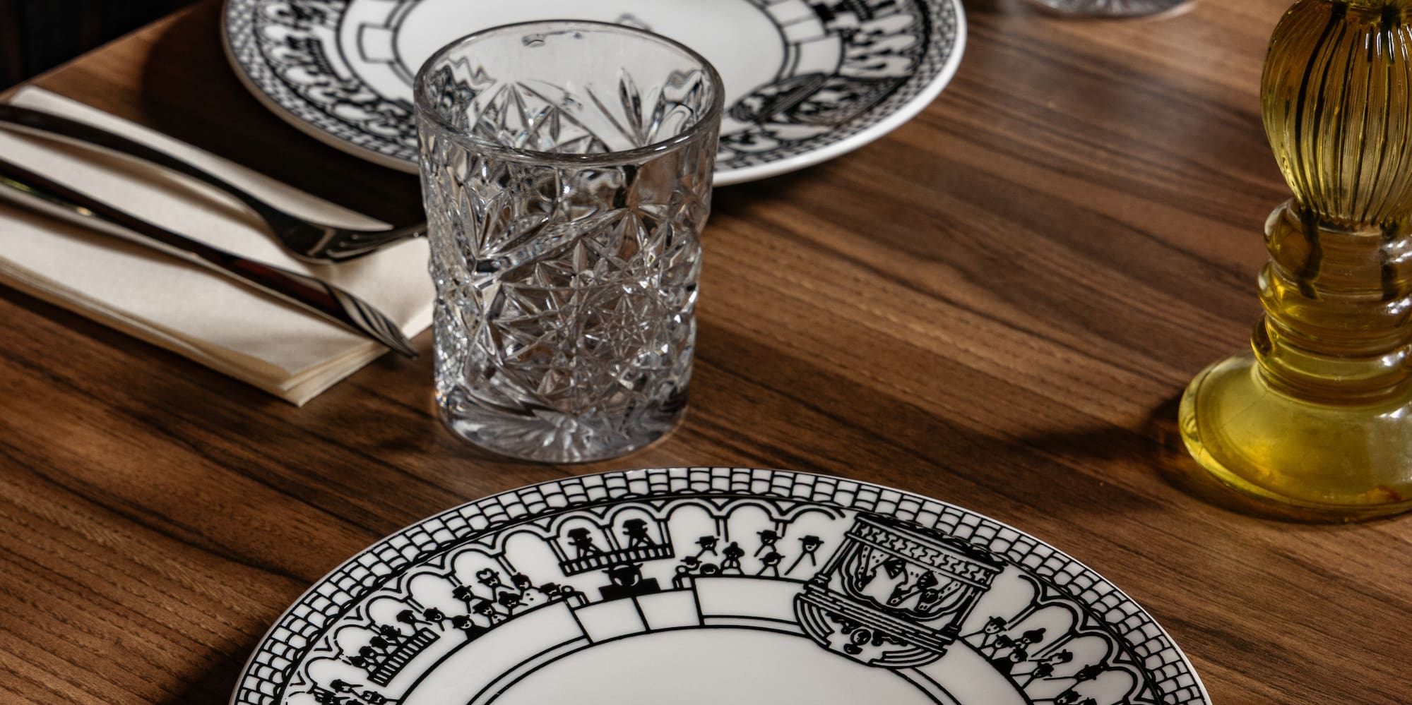 Mesa de restaurante con platos Burladero, vasos de cristal y cubiertos.