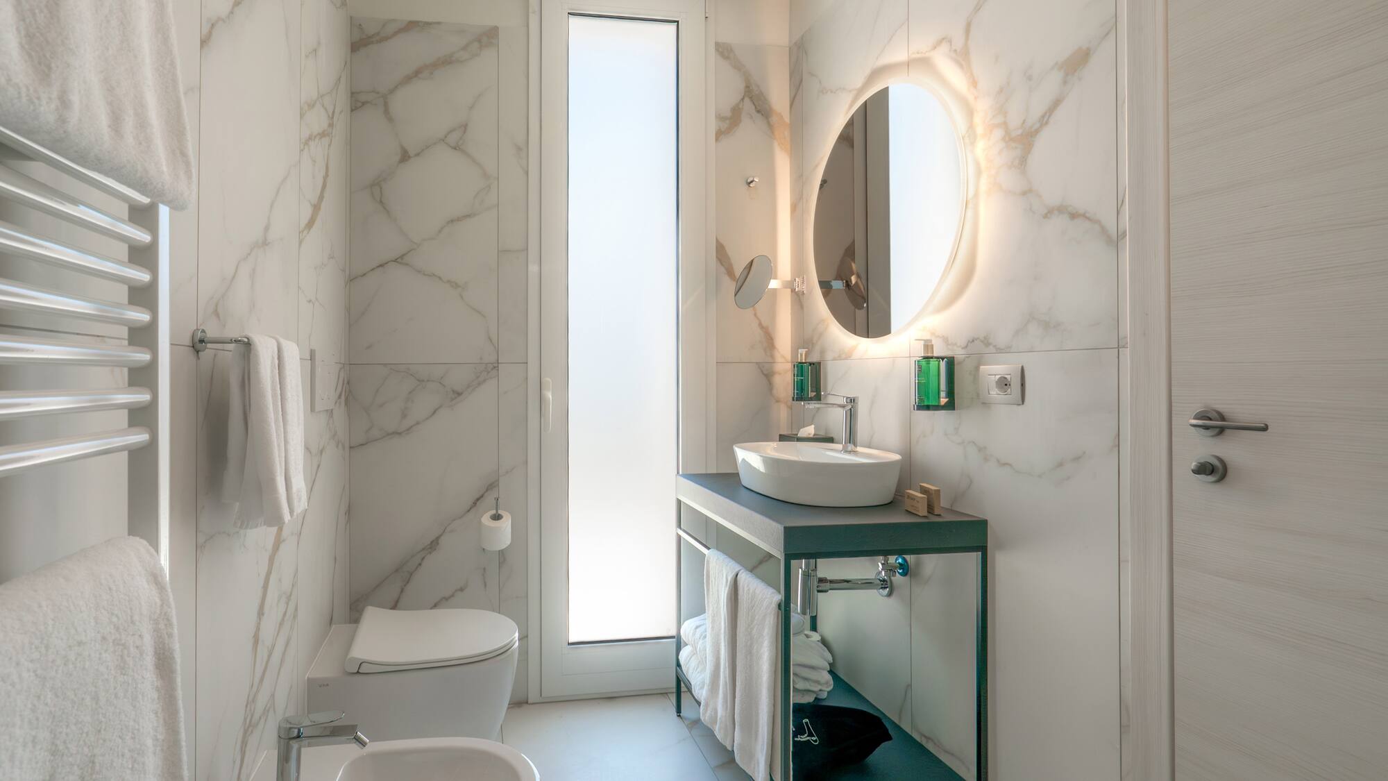 a bathroom with marble walls and a sink and toilet