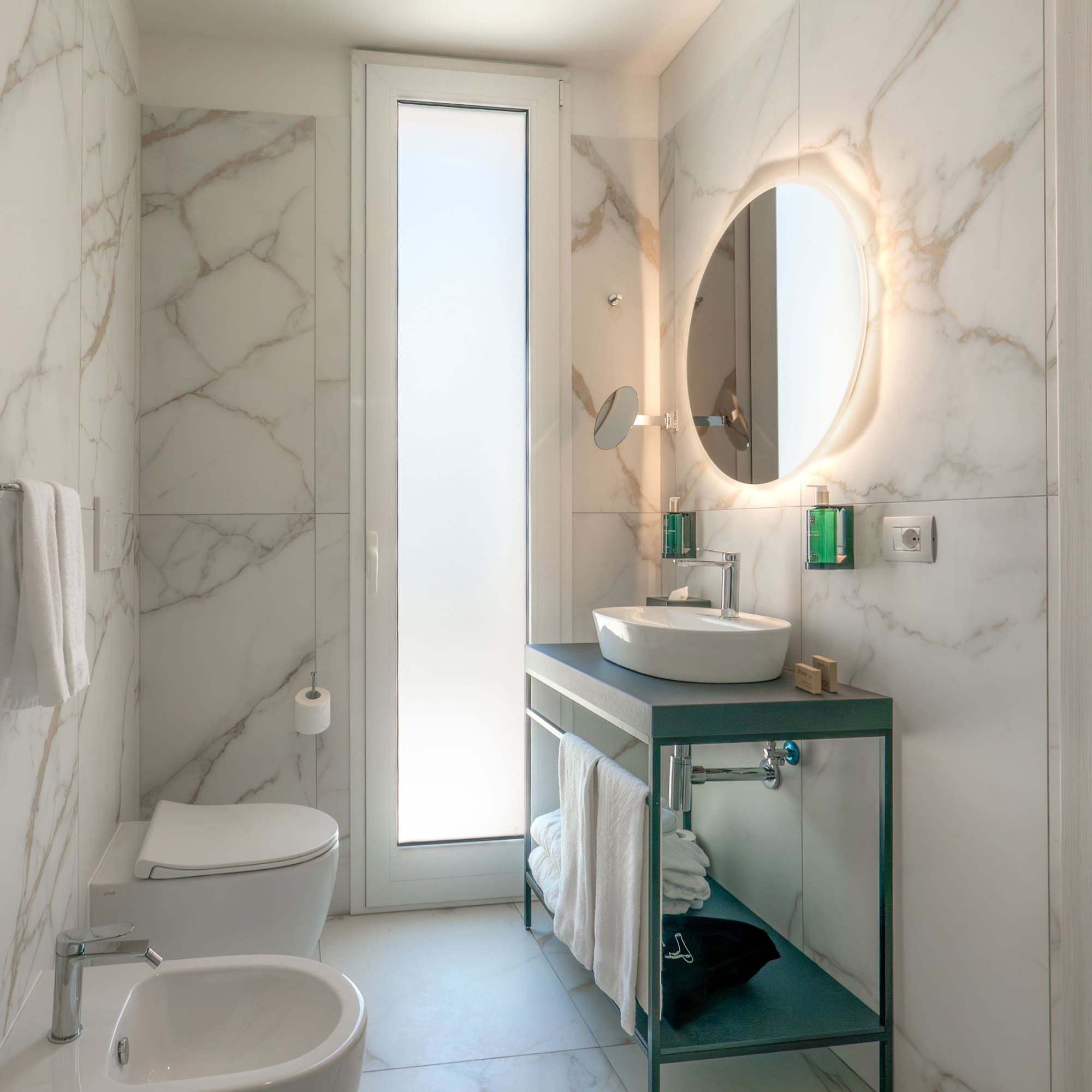 a bathroom with marble walls and a sink and toilet