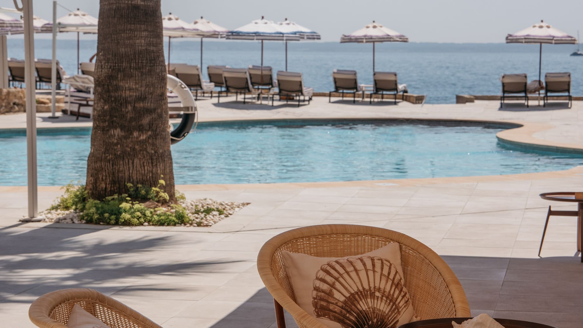 a patio with chairs and tables by a pool