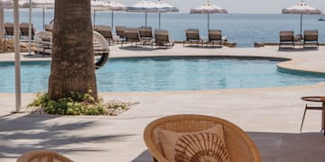 a patio with chairs and tables by a pool