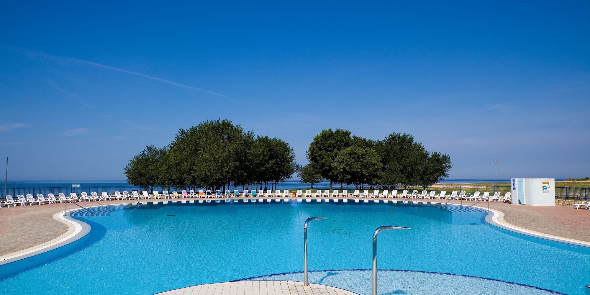 a pool with chairs and trees in the background