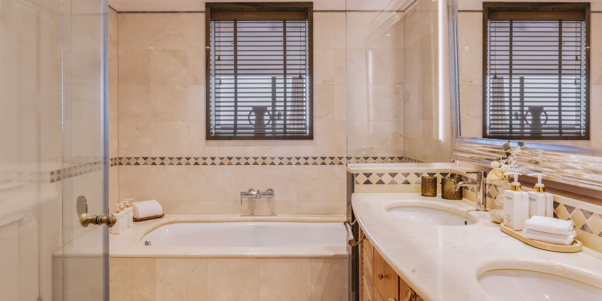 Luxurious marble bathroom with double vanity, bathtub, and glass shower.