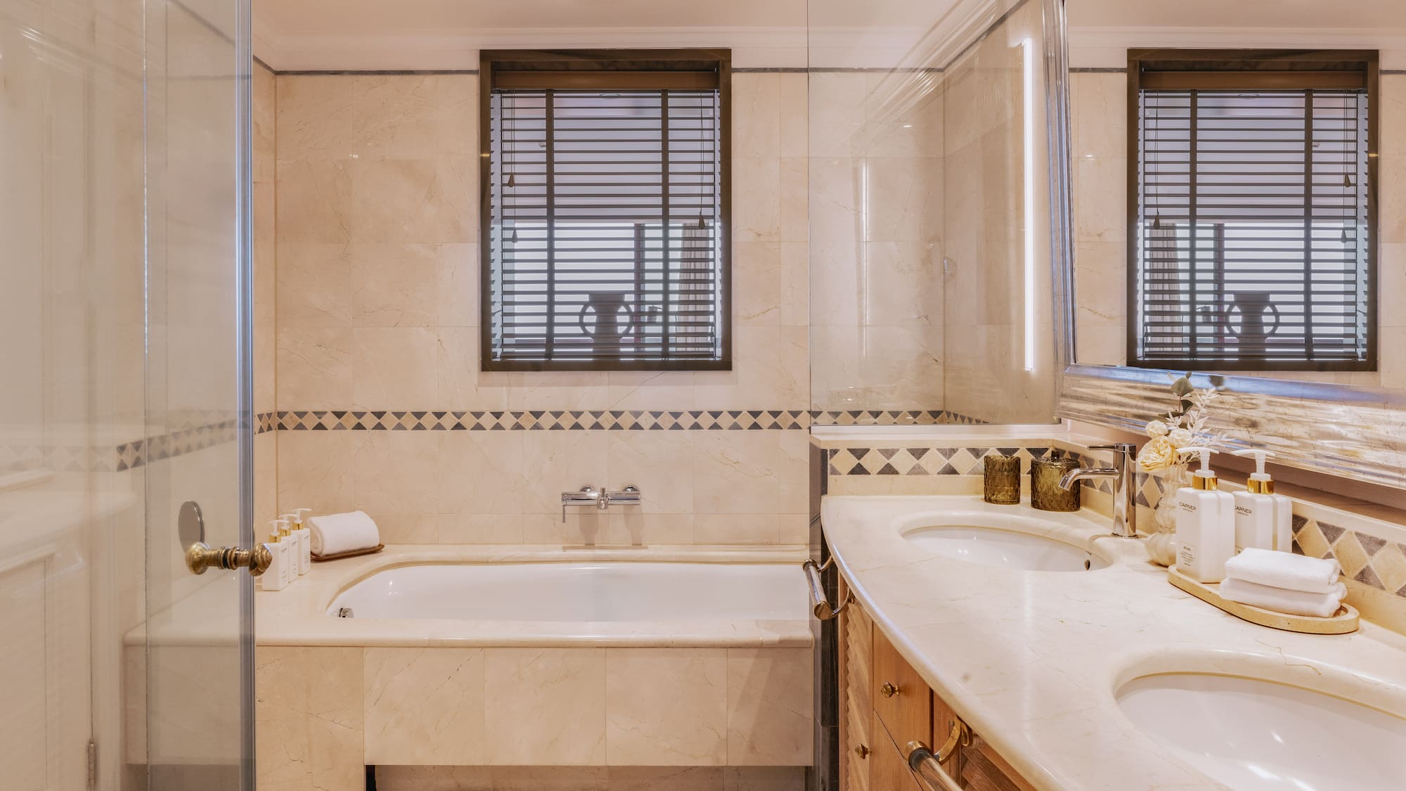 Luxurious marble bathroom with double vanity, bathtub, and glass shower.