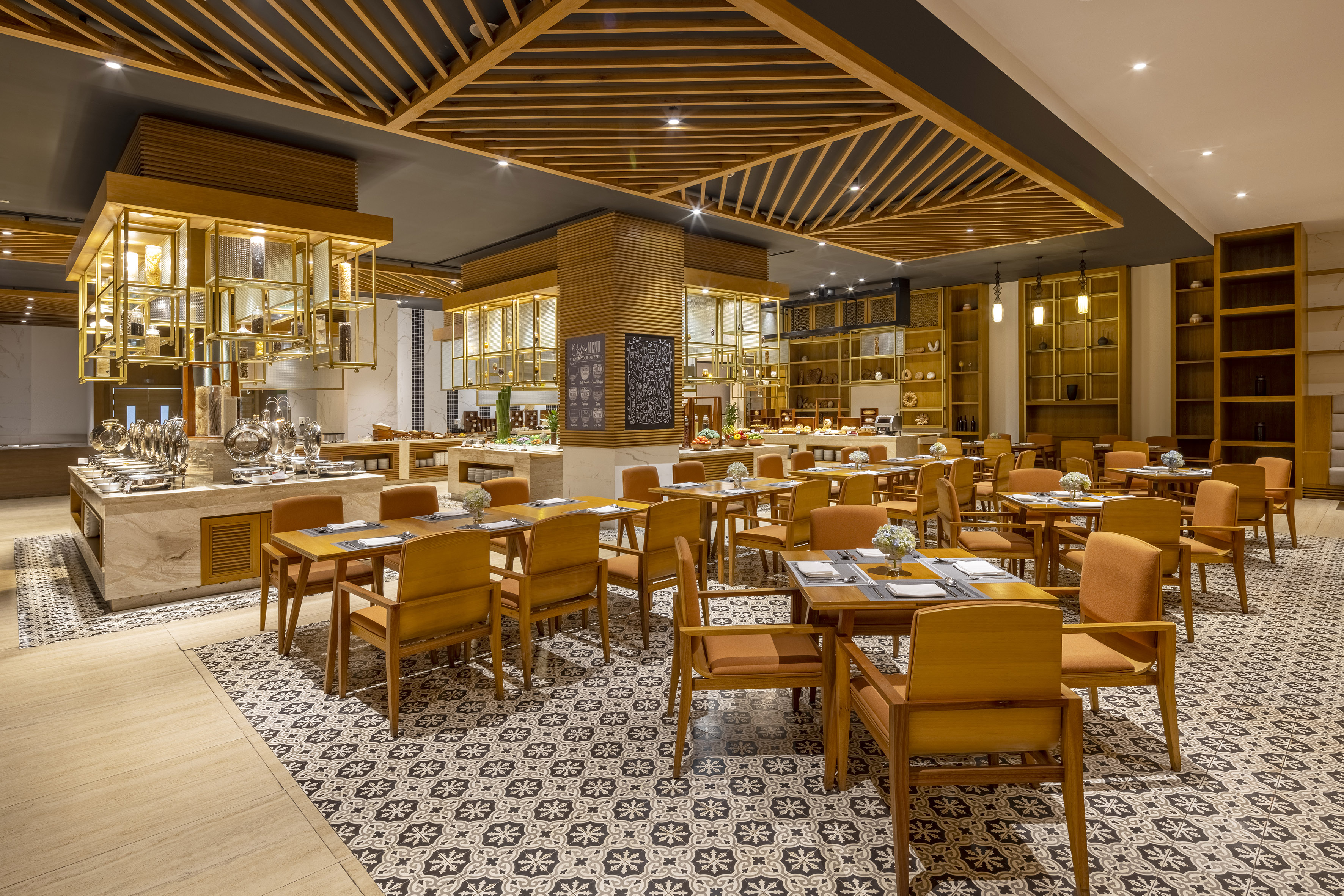 Hotel restaurant buffet with wooden furniture and patterned floor tiles.