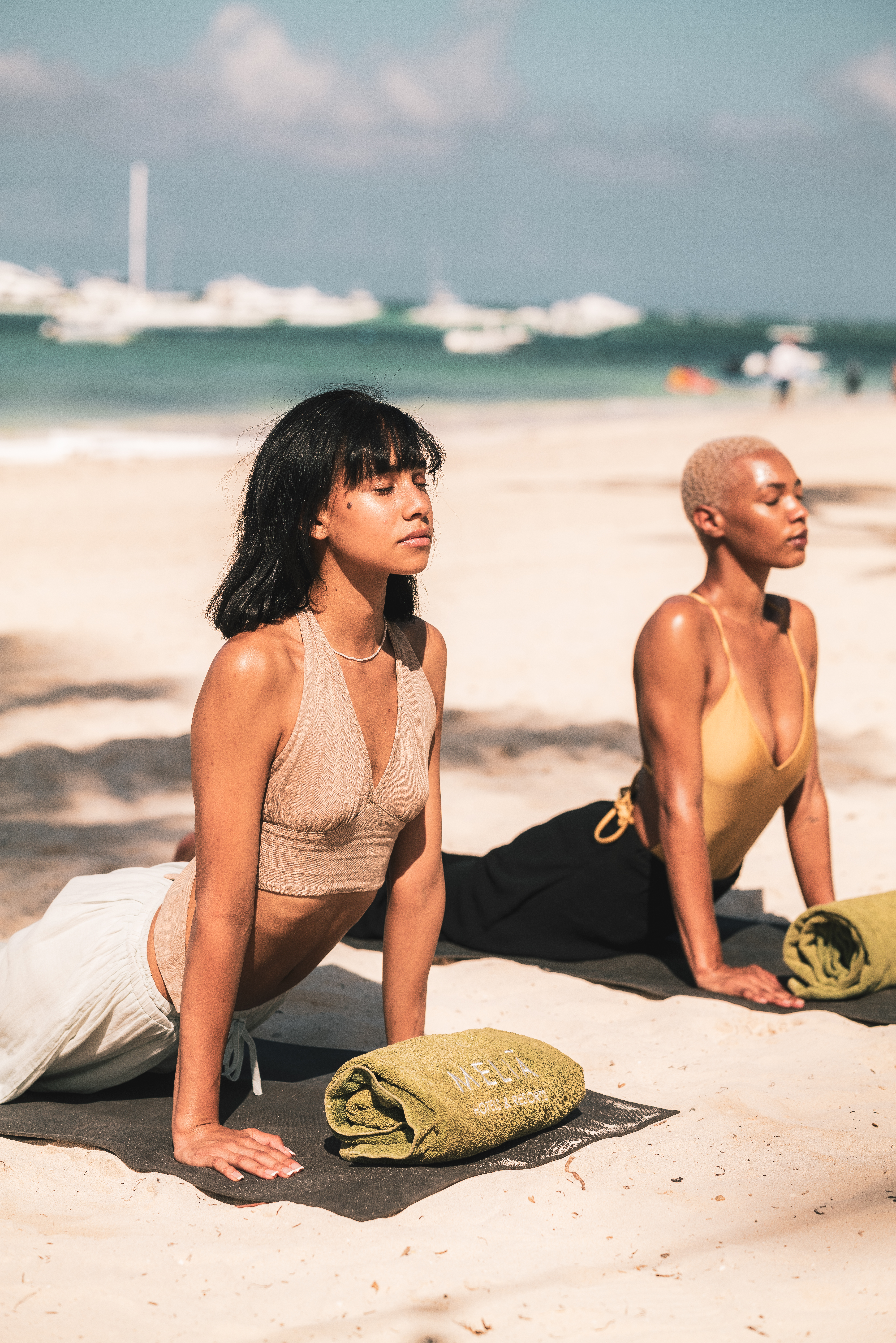 a couple of women doing yoga on the beach