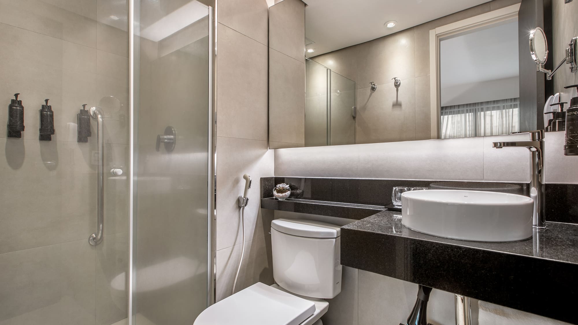 Banheiro moderno com pia sobreposta, vaso sanitário e box de vidro. - Deluxe Room Queen - Meliá Ibirapuera, São Paulo