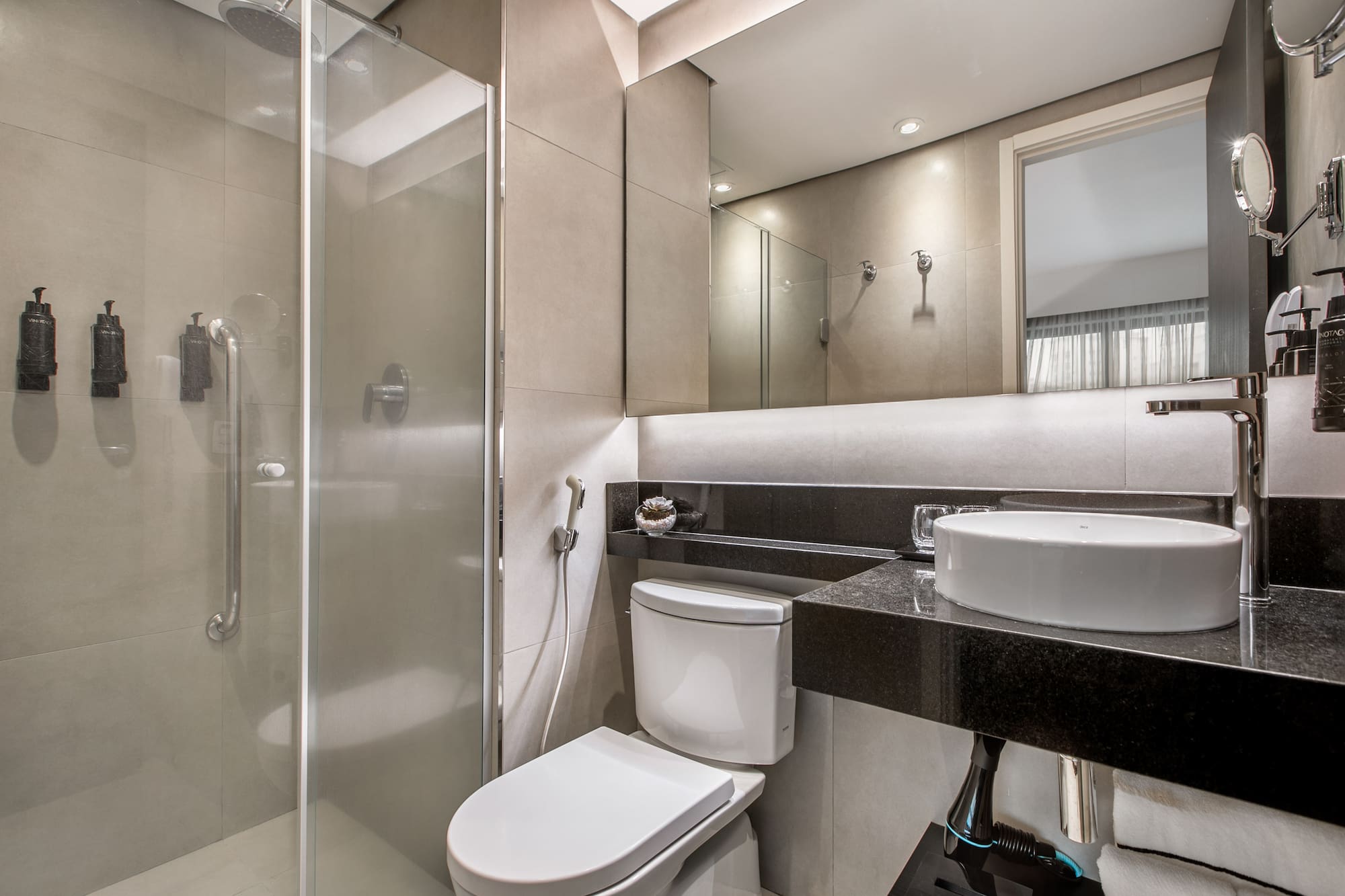 Banheiro moderno com pia sobreposta, vaso sanitário e box de vidro. - Deluxe Room Queen - Meliá Ibirapuera, São Paulo