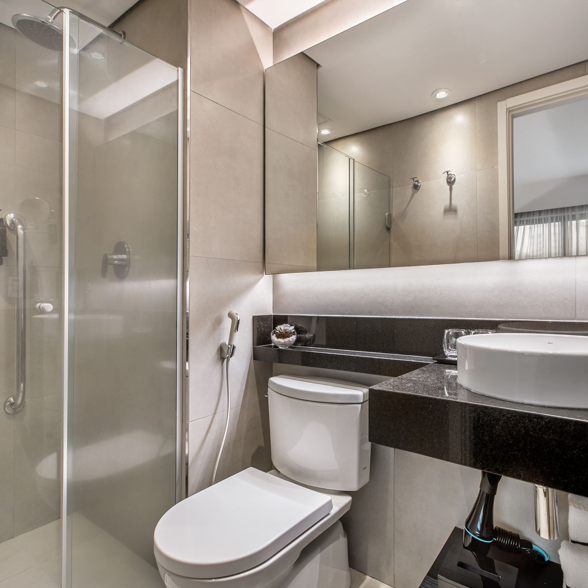 Banheiro moderno com pia sobreposta, vaso sanitário e box de vidro. - Deluxe Room Queen - Meliá Ibirapuera, São Paulo
