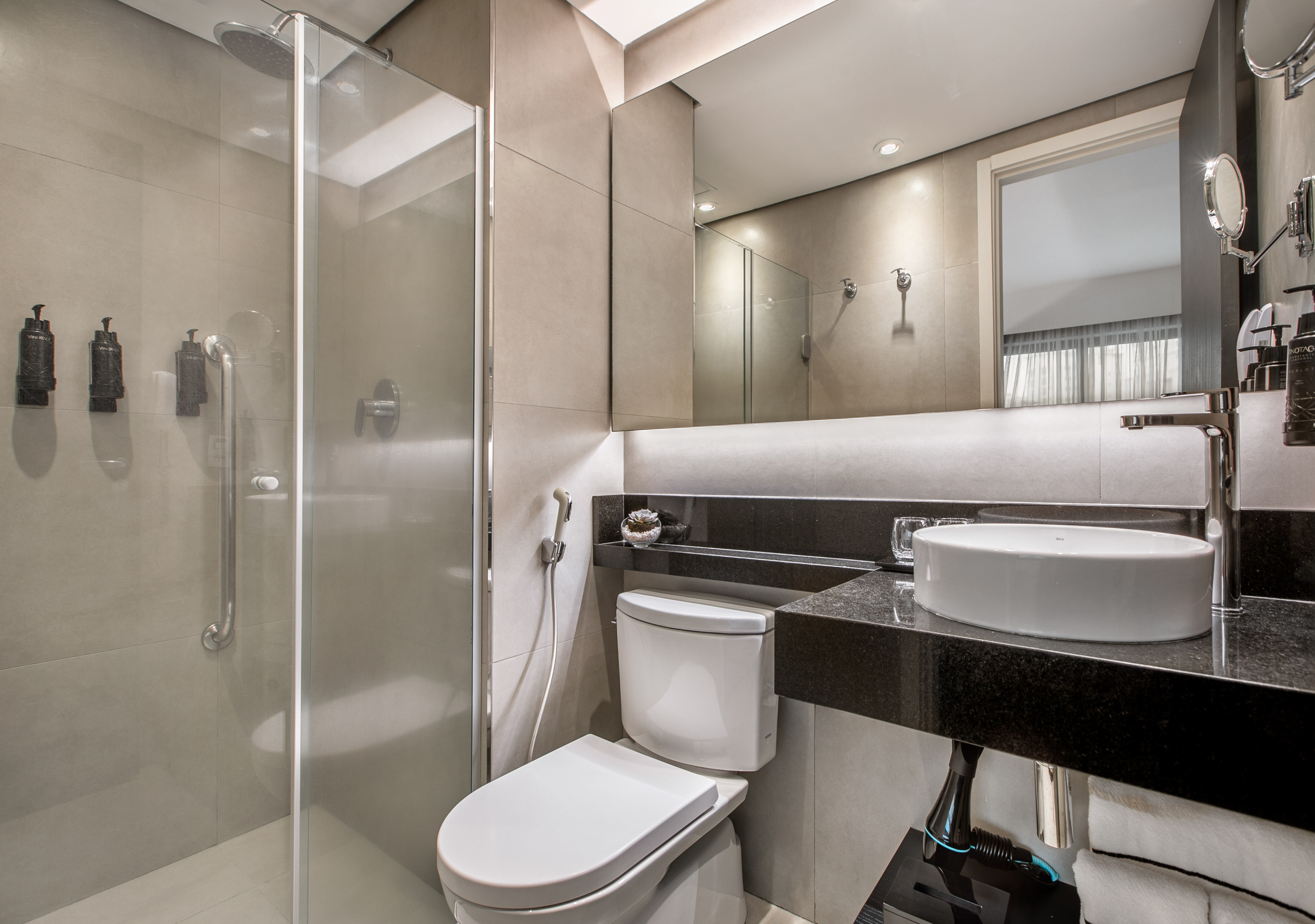 Banheiro moderno com pia sobreposta, vaso sanitário e box de vidro. - Deluxe Room Queen - Meliá Ibirapuera, São Paulo