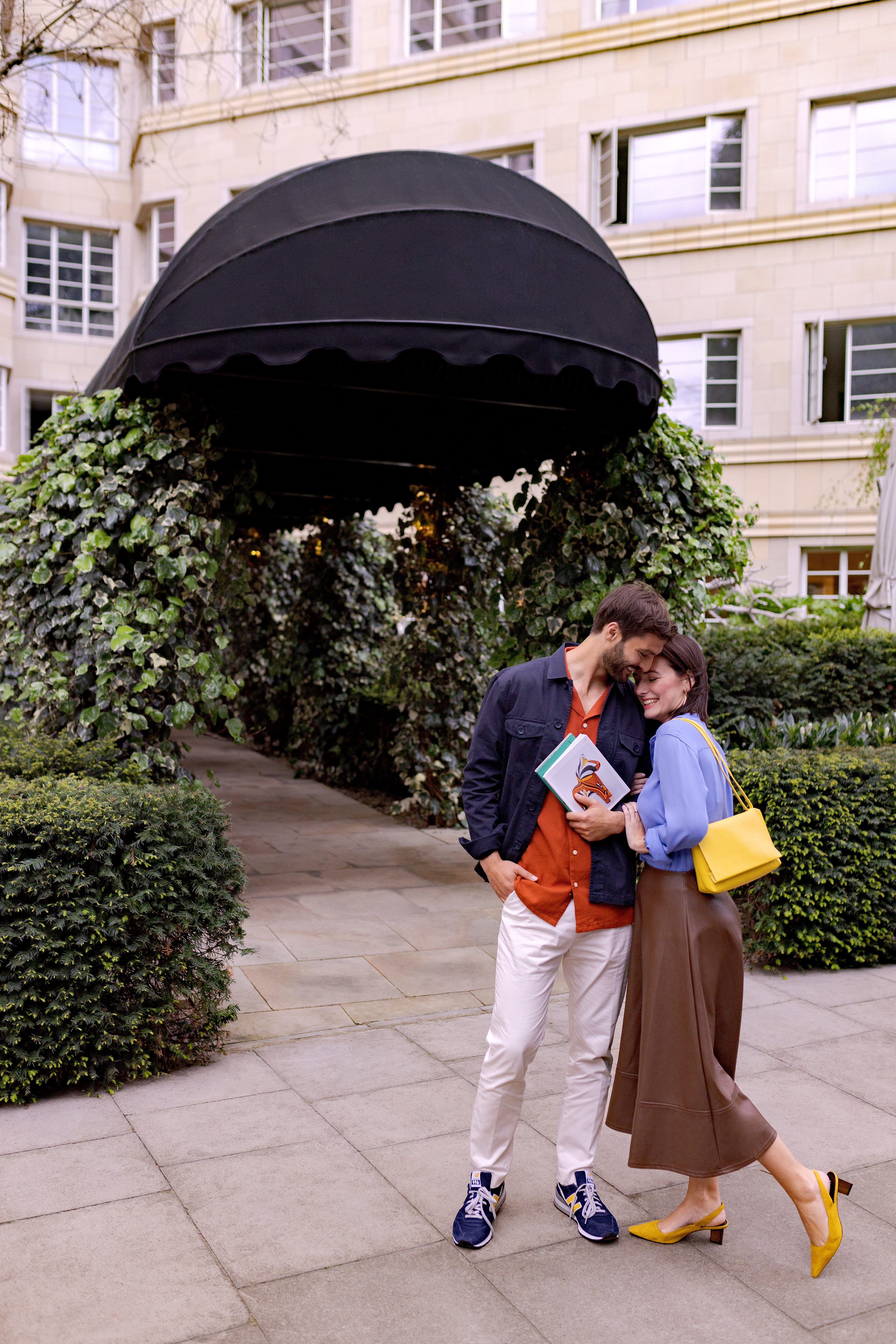 a man and woman hugging under a black umbrella