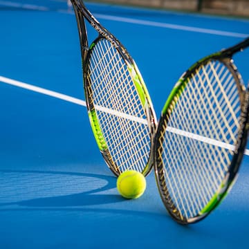two tennis rackets and a ball on a blue court