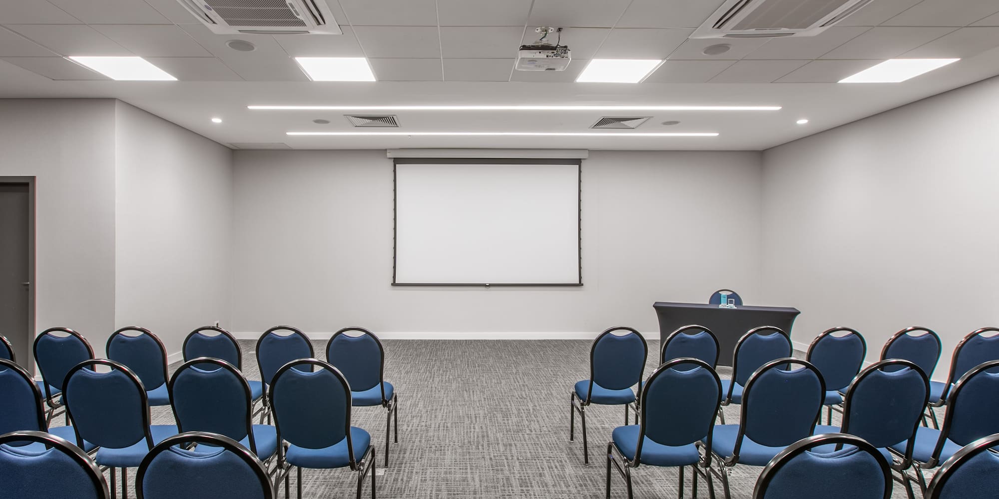 a room with blue chairs and a projection screen