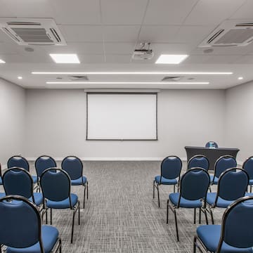 a room with blue chairs and a projection screen