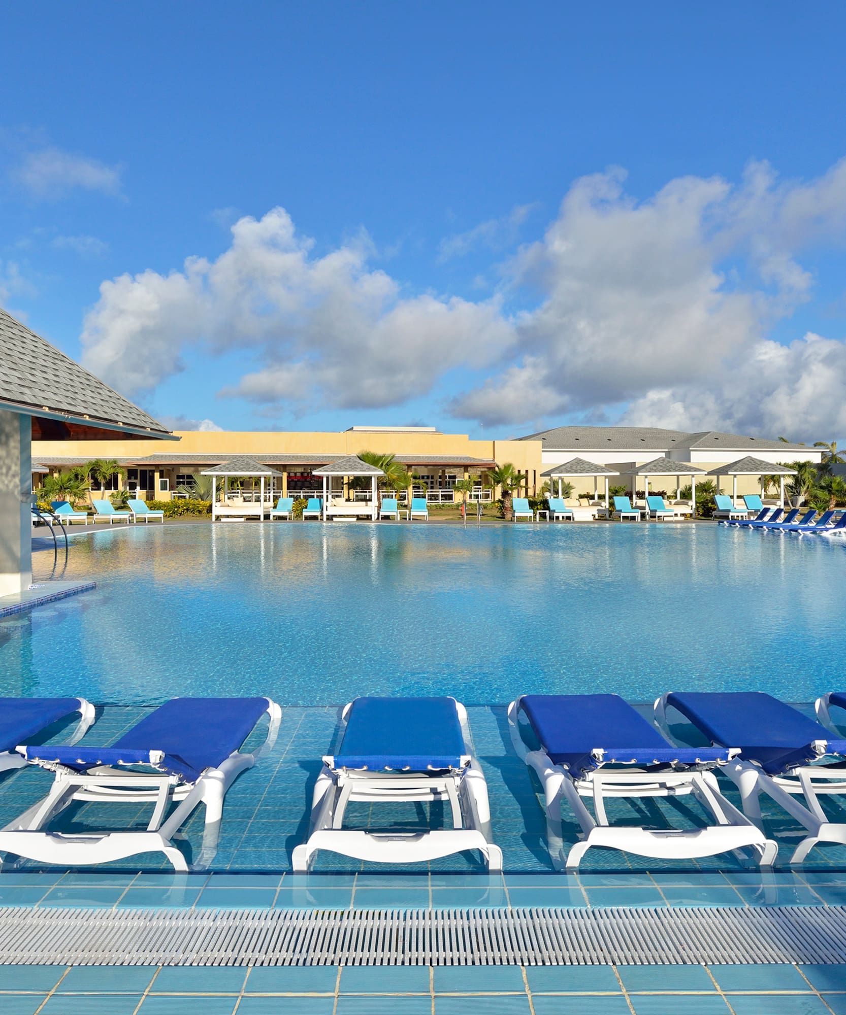 a pool with lounge chairs and a building