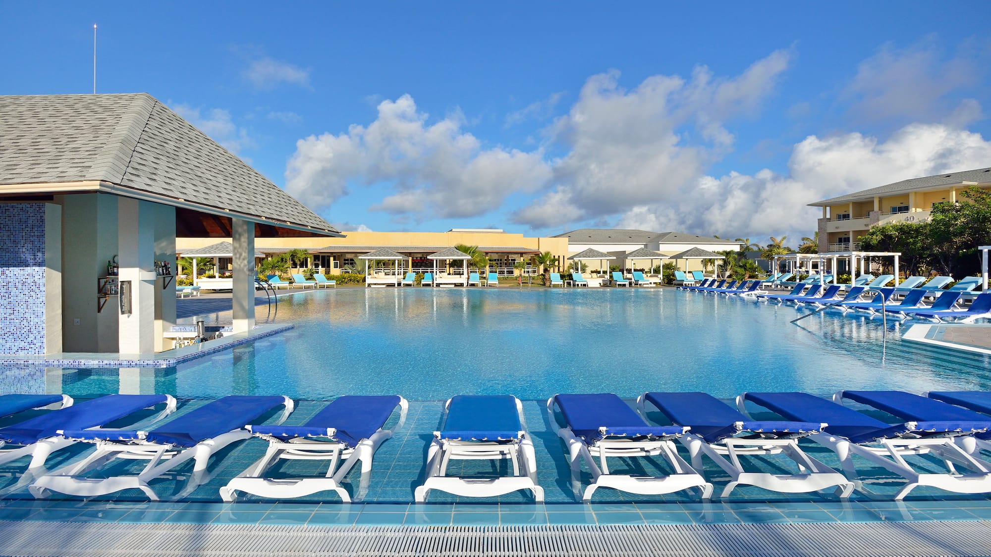 a pool with lounge chairs and a building