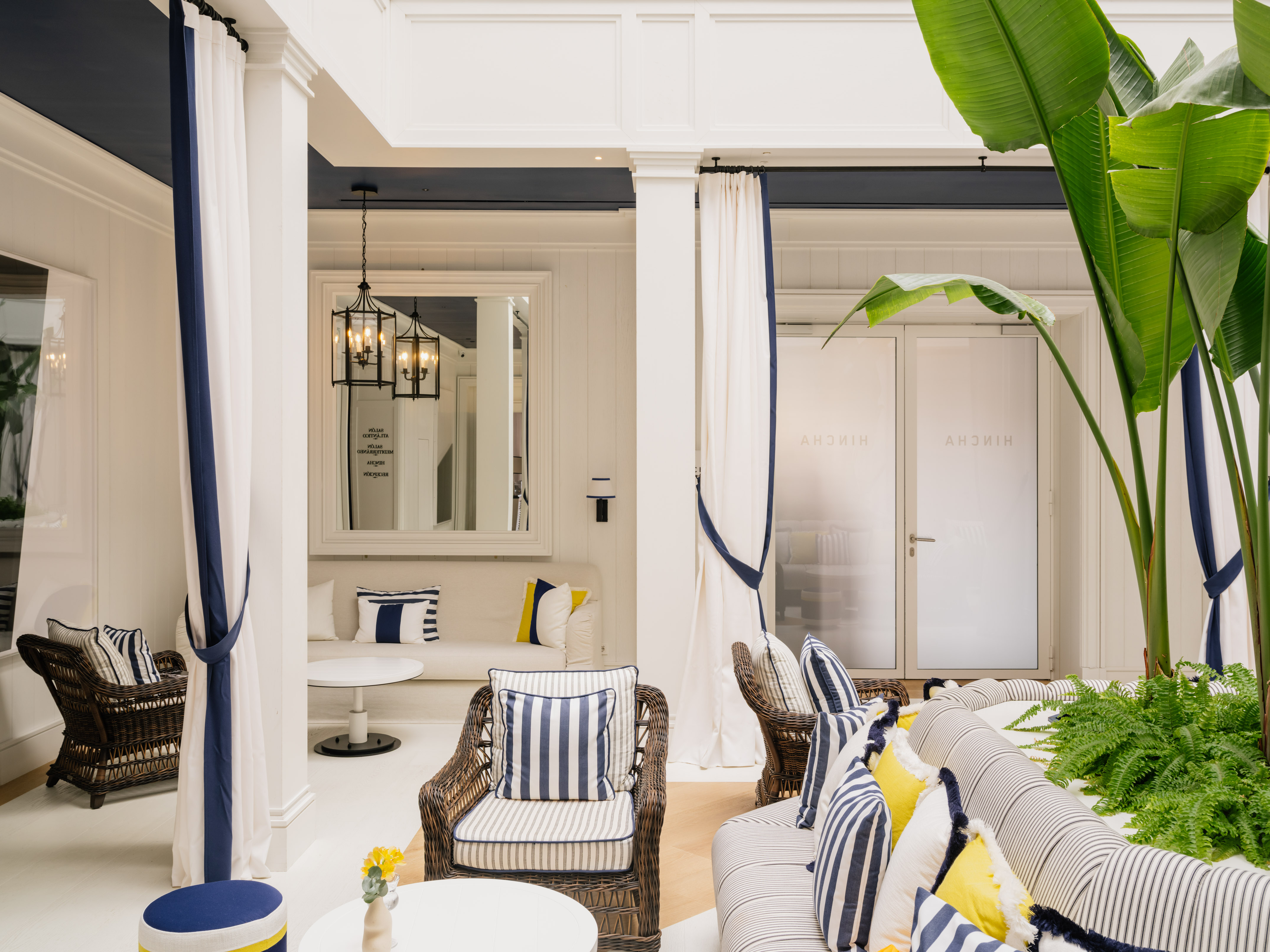 Nautical lounge with striped cushions, rattan chairs, and tropical plants.