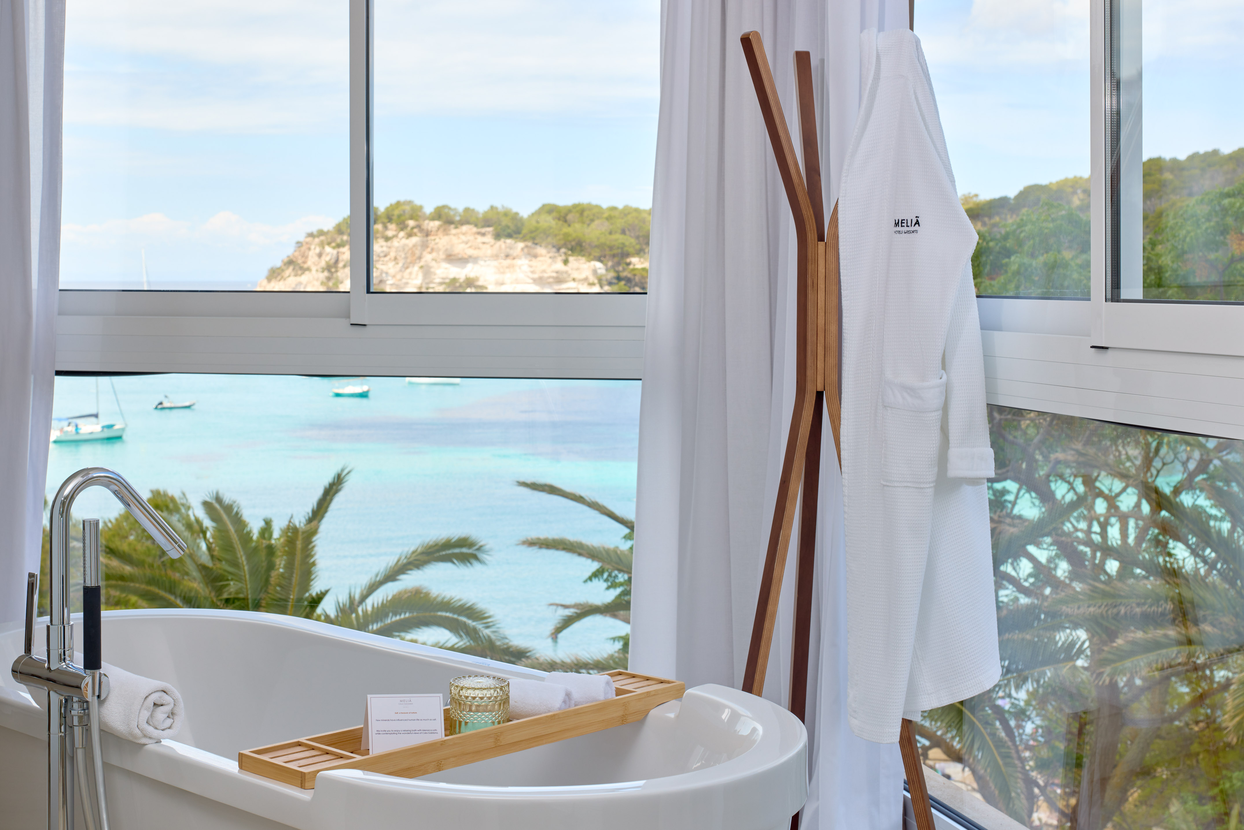 Luxury bathroom with ocean view, freestanding tub, and Meliã bathrobe.