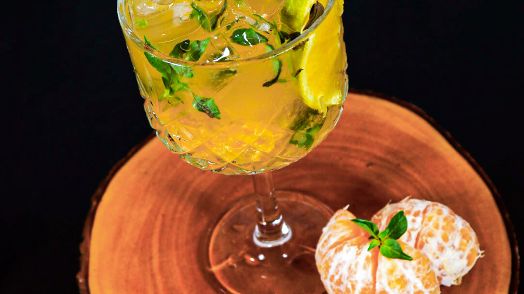 a glass of liquid with ice and mint on a wood surface